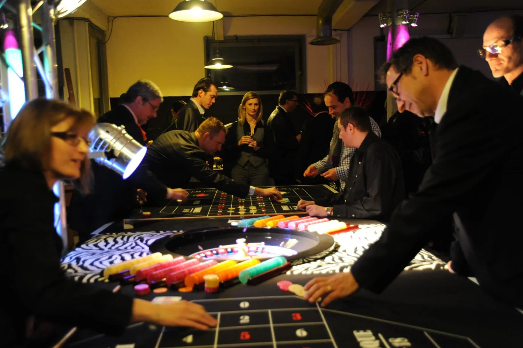 Invités autour de la roulette, jetons colorés posés sur le tapis