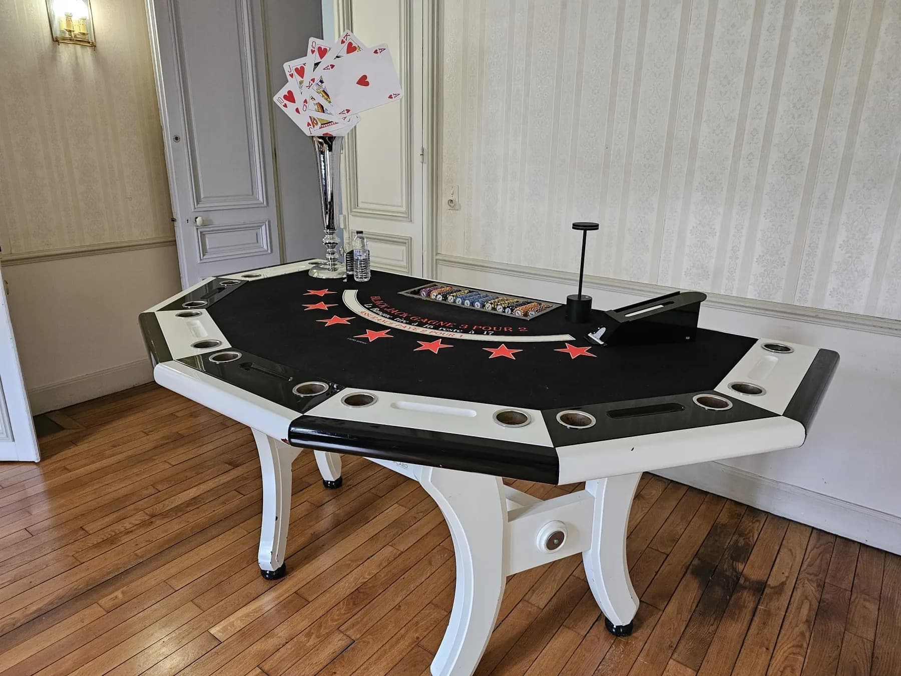 Table de blackjack blanche dans un salon aux murs clairs et parquet, flûte de cartes