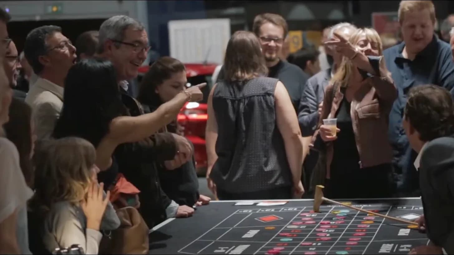 Des invités rient et commentent la partie autour d’une table de roulette, lors d’une soirée casino