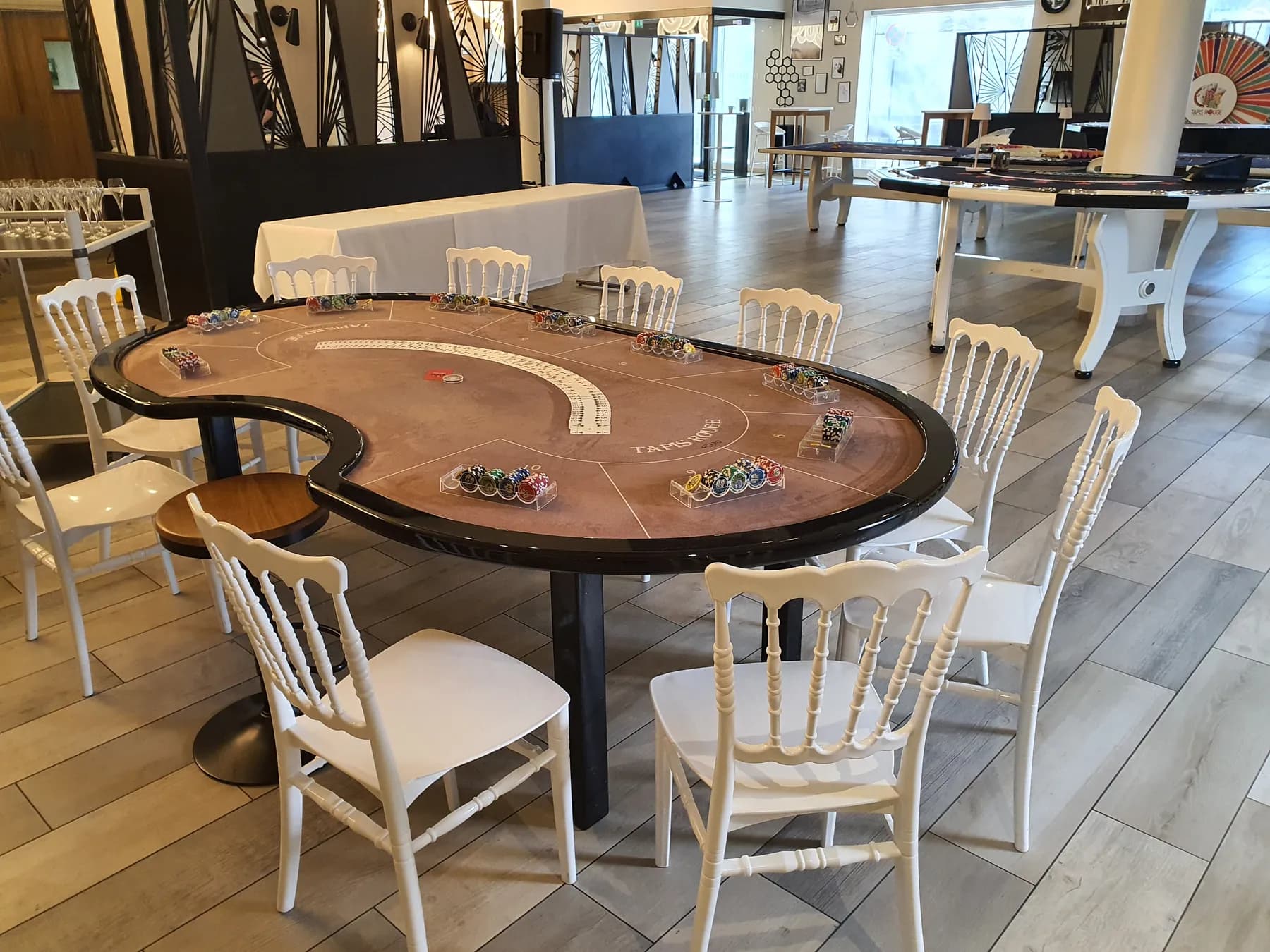 Table de poker en demi-lune, chaises blanches, dans une salle de réception
