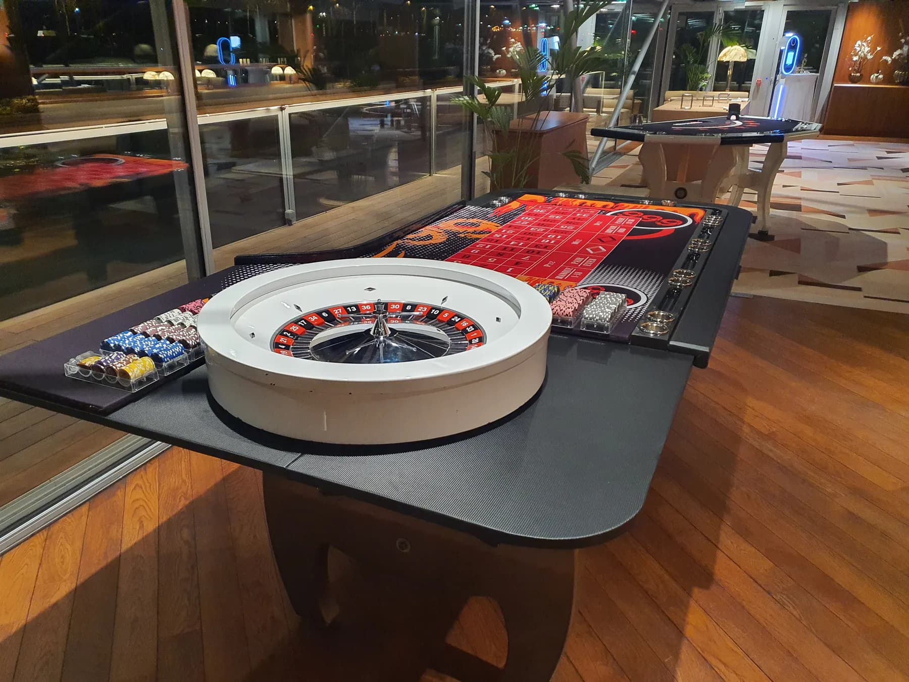 Roulette anglaise sur une table noire, parquet et baies vitrées de nuit
