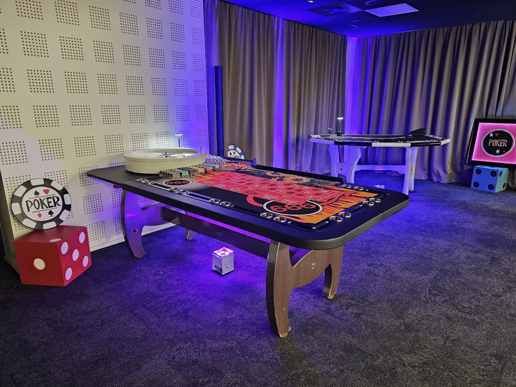 Table de jeu éclairée en violet dans une salle, avec un dé rouge géant