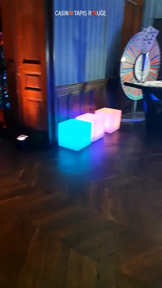 Cubes lumineux sur un parquet, roue de la chance au fond d’un salon lambrissé